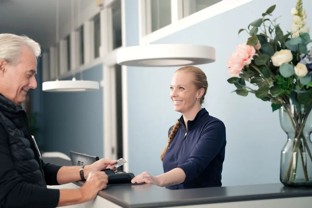 Receptionist tager imod patient ved skranke hos Tandlægerne Ølandshus